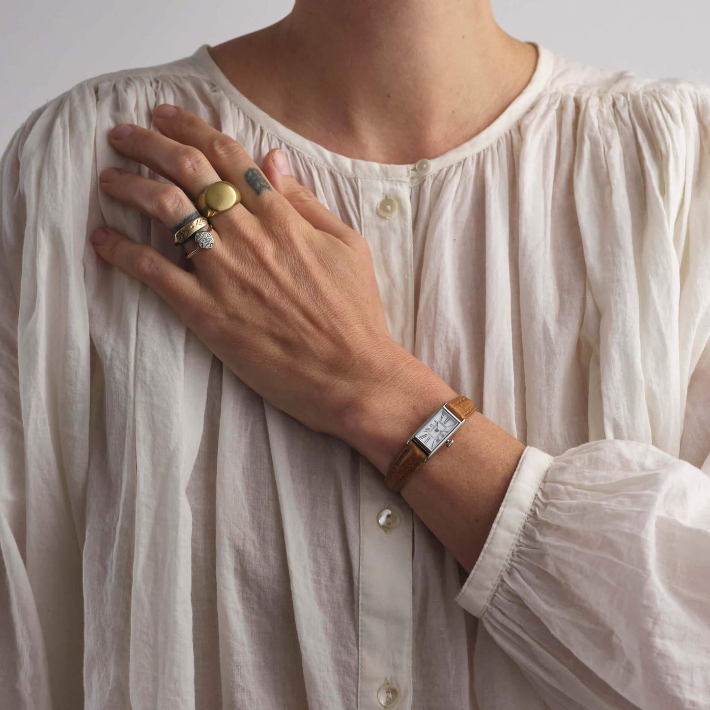 woman in white top wearing tan and silver kimsey watch
