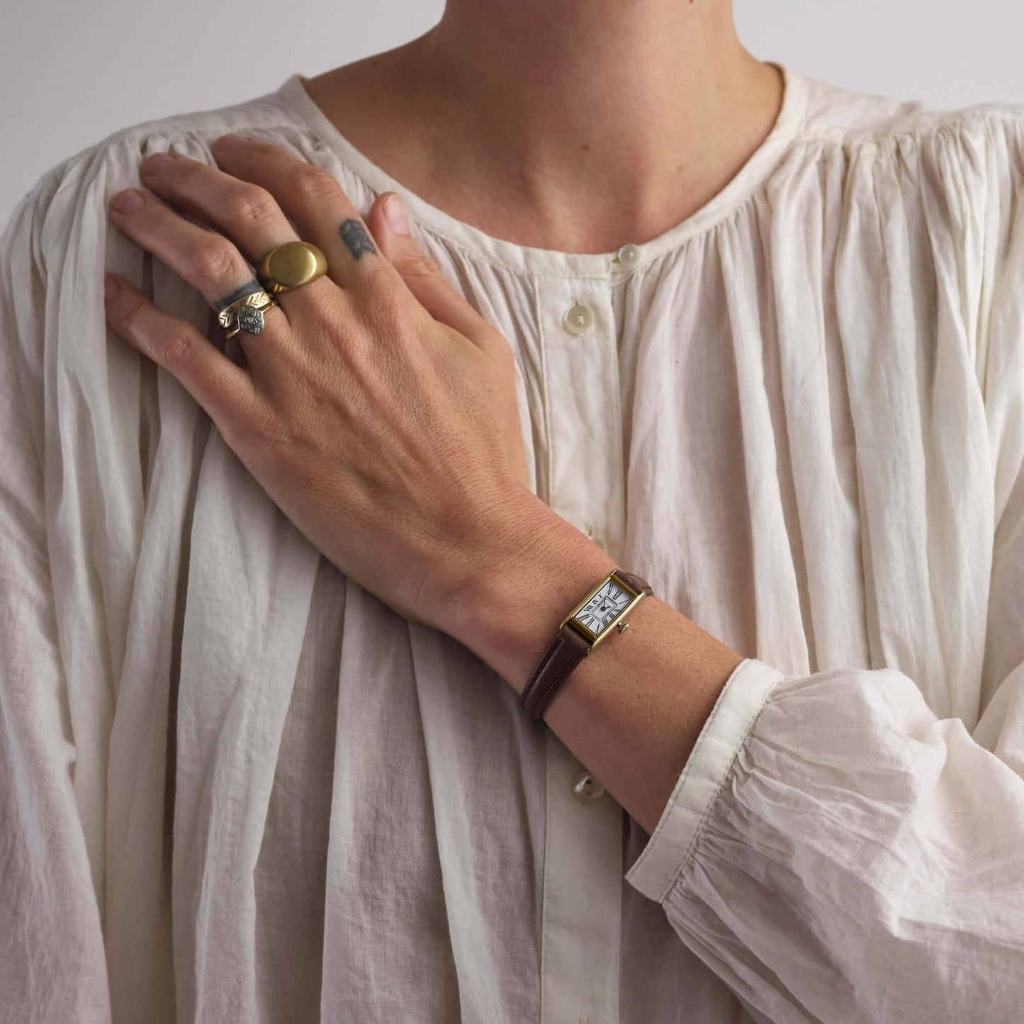 woman in white top wearing brown and gold kimsey watch