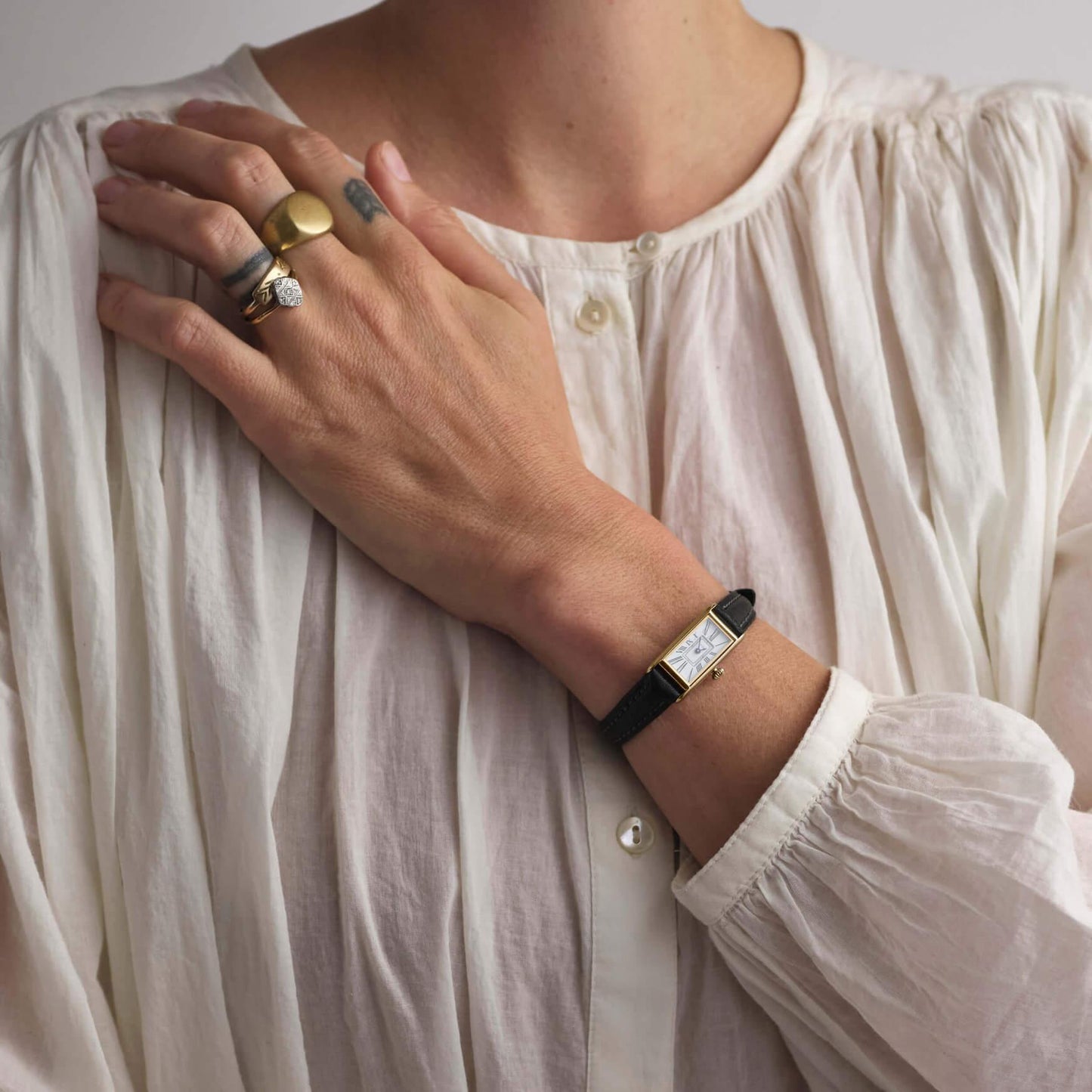 woman in white top wearing black and gold kimsey watch 
